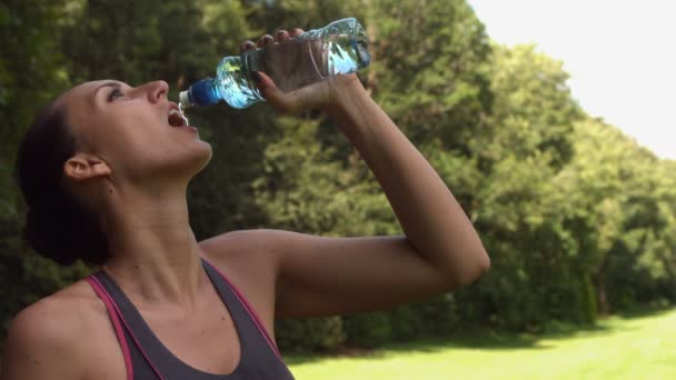 Sportliche Brünette trinkt aus Wasserflasche — Stockvideo