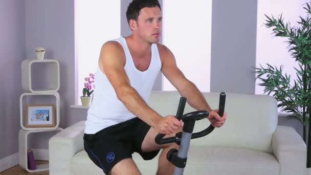 Hombre deportivo guapo entrenando en bicicleta estática — Vídeos de Stock