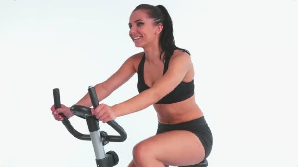 Morena alegre desportiva usando bicicleta de exercício — Vídeo de Stock
