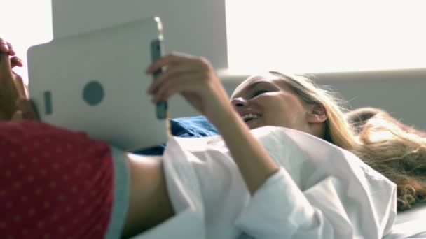 Гарненька модель, використовуючи планшет, лежачи на ліжку — стокове відео