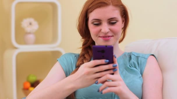 Mooie brunette glimlachend en SMS op smartphone — Stockvideo