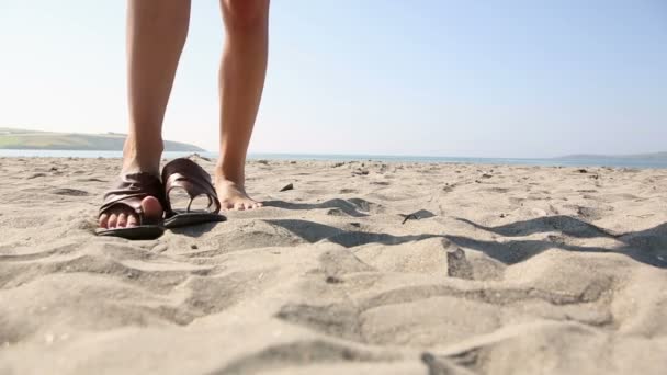 Жінка кладе сандалі на пляж — стокове відео