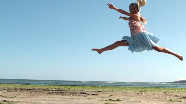 Attractive blonde doing ballet jump on beach — Stock Video