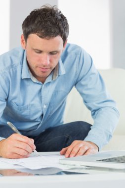 Content casual man writing on sheets paying bills clipart