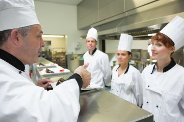 Head chef rating the plate of one of his apprentices clipart
