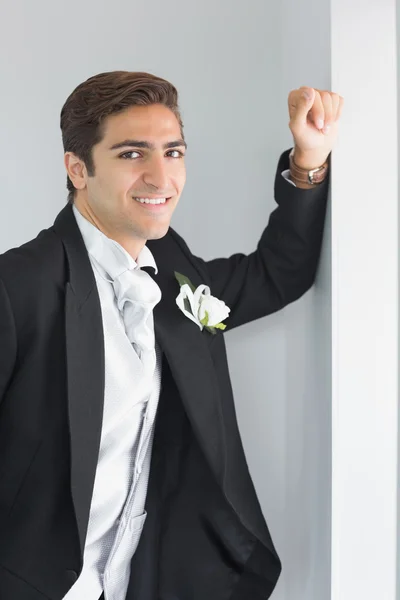 Cheerful young bridegroom leaning against wall — Stock Photo, Image