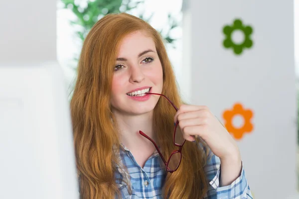 Beautiful redhead sitting at her desk and smiling — Stock Photo, Image