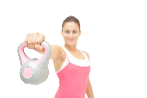Smiling toned brunette showing grey and pink kettlebell — Stock Photo, Image