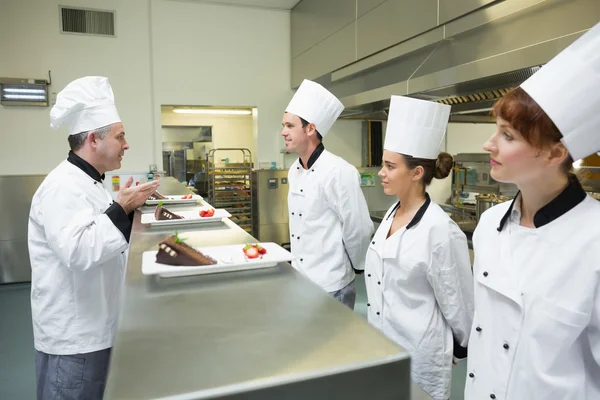 Drei Köche präsentieren dem Chefkoch ihre Dessertteller — Stockfoto