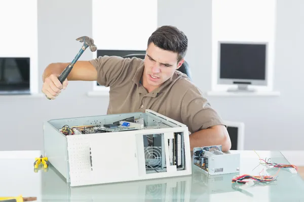 Attractive angry computer engineer destroying computer with hammer — Stock Photo, Image