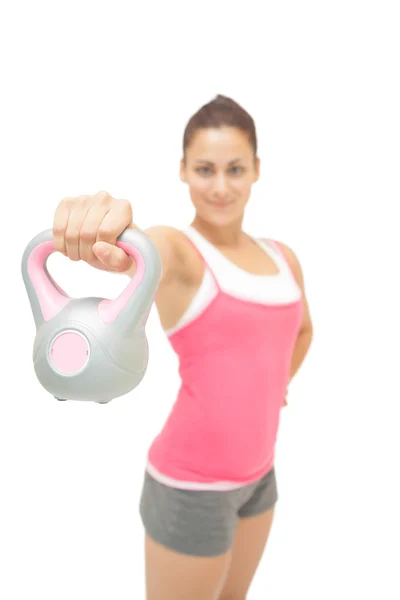 Smiling sporty brunette showing grey and pink kettlebell — Stock Photo, Image