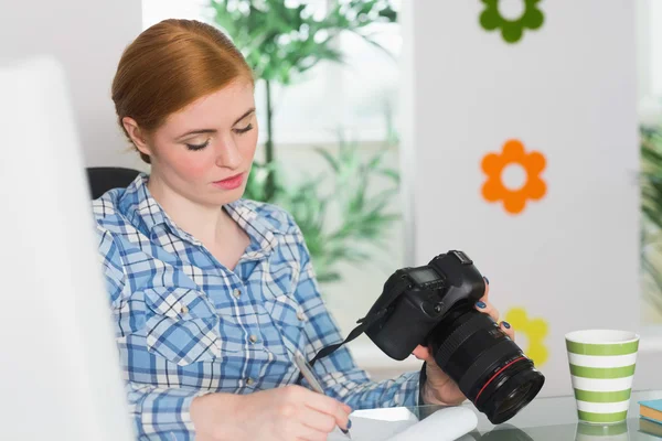 彼女のカメラを保持している彼女の机に座っての写真家に焦点を当ててください。 — ストック写真