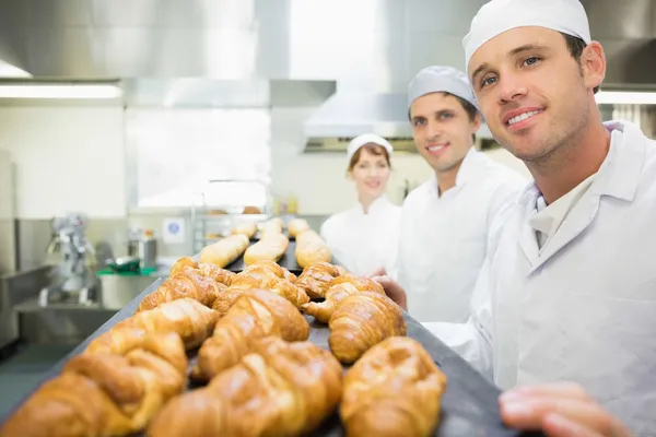 Tres jóvenes panaderos posando en una panadería — Foto de Stock