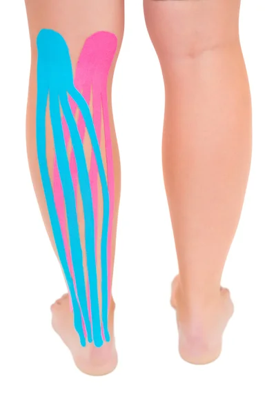 Patients leg with applied pink and blue kinesio tape — Stock Photo, Image