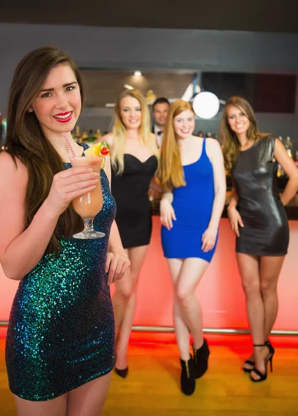 Lächelnde Frau vor ihren Freunden mit Cocktail — Stockfoto