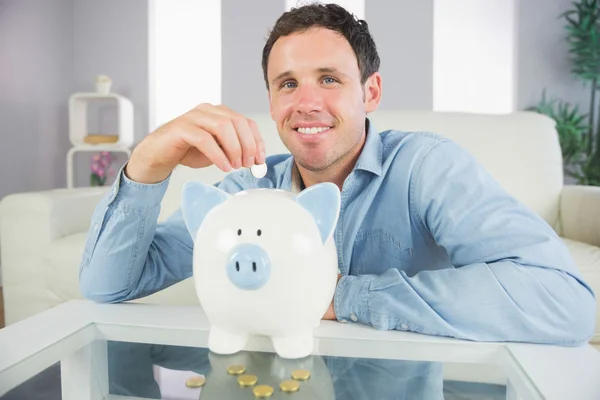 Hombre casual bien parecido poner moneda en alcancía — Foto de Stock