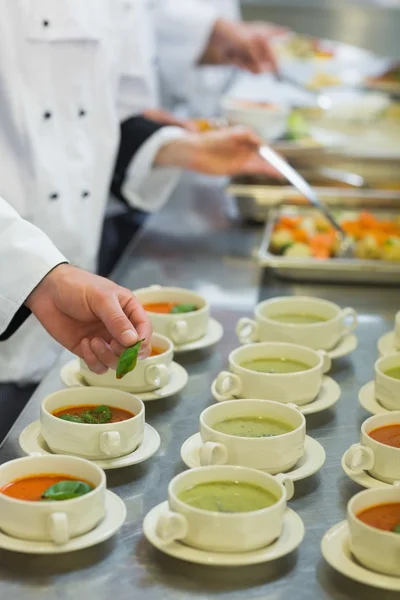Bowls with soup being garnished — Stock Photo, Image