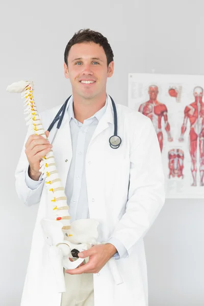 Bonito médico alegre segurando modelo de esqueleto — Fotografia de Stock
