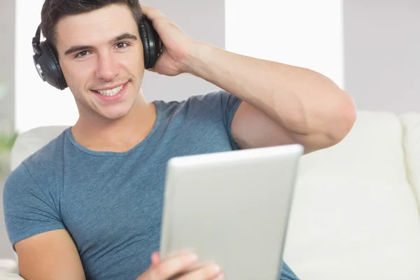 Hombre guapo alegre usando tableta escuchando música — Foto de Stock