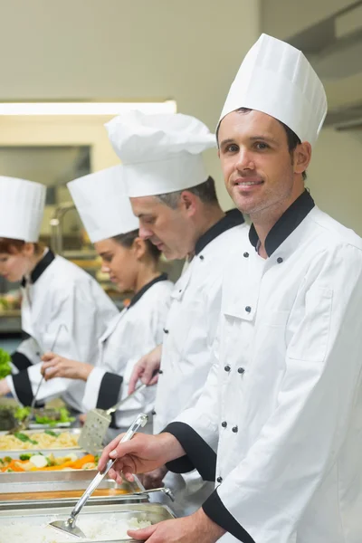 Happy chef standing at serving tray — Stock Photo, Image