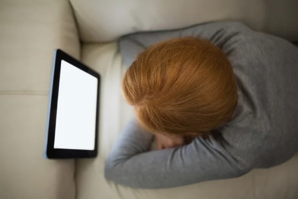 Rödhårig liggande på soffan tittar på hennes TabletPC — Stockfoto