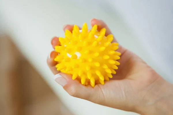 Gros plan de la main gauche féminine tenant une boule de massage jaune — Photo