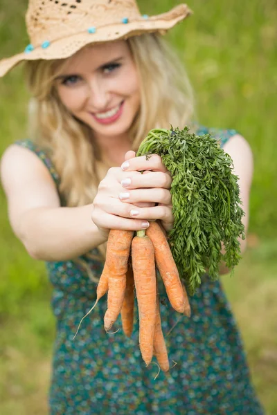 Mujer sonriente presentando algunas zanahorias — Foto de Stock