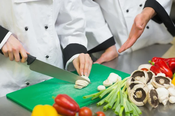 Chef gesticolando i suoi colleghi affettati funghi — Foto Stock