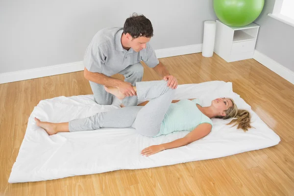 Physiotherapist treating patients leg on a mat on the floor — Stock Photo, Image