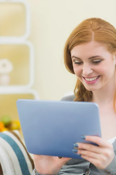 Fröhlicher Rotschopf sitzt mit Tablet auf der Couch — Stockfoto