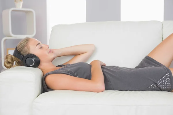 Casual ήρεμη ξανθιά ξαπλωμένη στον καναπέ, ακούγοντας μουσική — Φωτογραφία Αρχείου