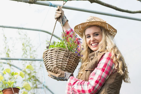 Mooie blonde tonen een opknoping bloemmand — Stockfoto