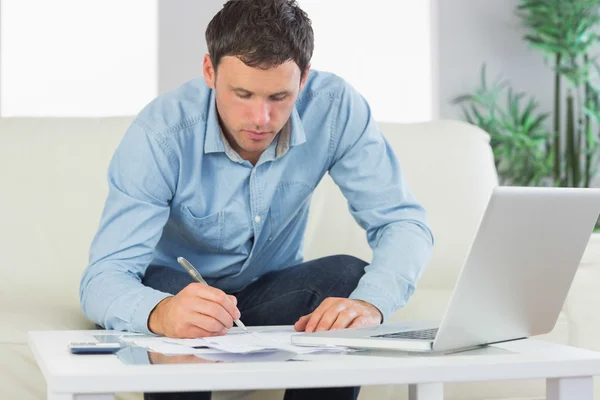 Hombre casual serio escribiendo en hojas pagando facturas —  Fotos de Stock