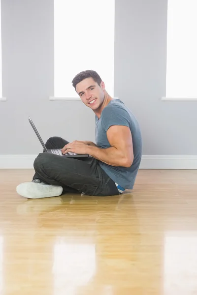 바닥에 앉아 노트북을 사용 하 여 웃는 잘생긴 남자 — 스톡 사진
