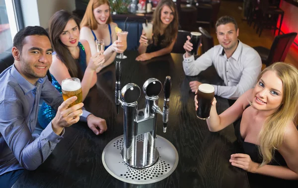 Attractive friends raising glasses up smiling at camera — Stock Photo, Image