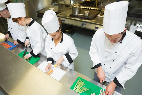 Vier chef-koks bereiden van voedsel aan balie — Stockfoto