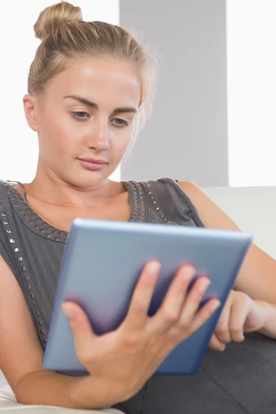 Casual sério loira relaxante no sofá usando tablet — Fotografia de Stock