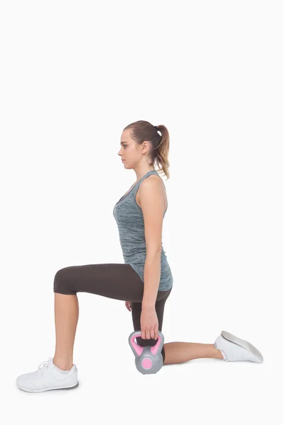 Mulher loira treinando com sino chaleira enquanto lunging — Fotografia de Stock