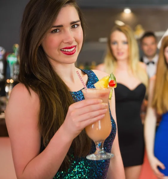 Attractive woman standing in front of her friends holding cocktail — Stock Photo, Image