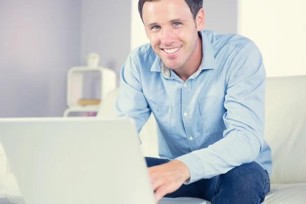 Cheerful casual man using laptop and looking at camera — Stock Photo, Image