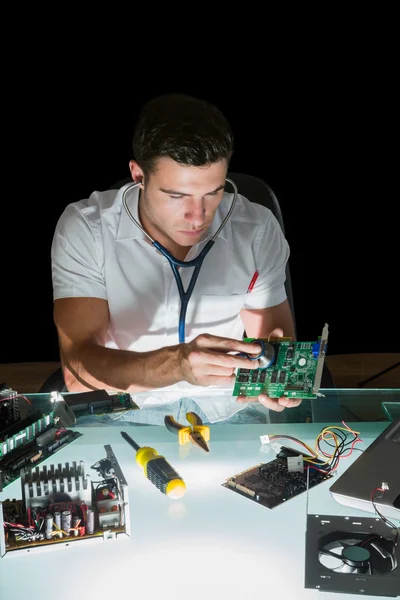 Attractive computer engineer examining hardware with stethoscope by night — Stock Photo, Image