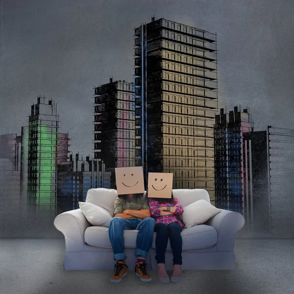 Couple sitting on couch in front of painted city — Stock Photo, Image