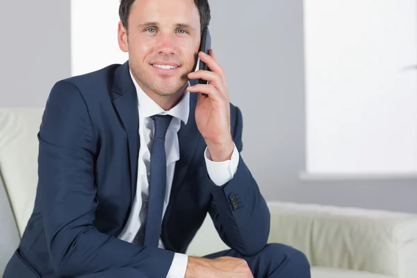 Sorrindo bonito empresário telefonando e sentado no sofá — Fotografia de Stock