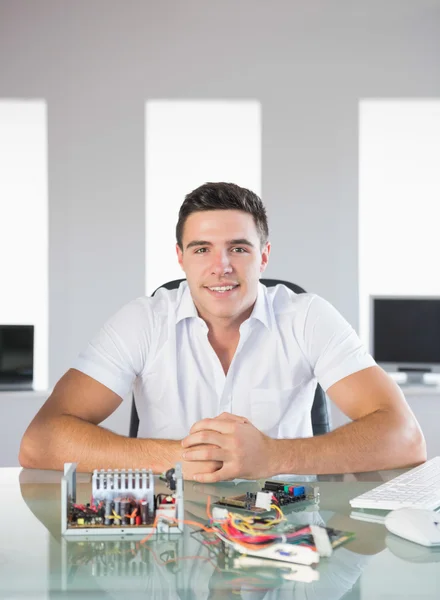 Ingeniero informático guapo sentado en el escritorio sonriendo a la cámara — Foto de Stock