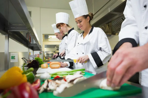 Fyra kockar tillagar maten vid disken i rad — Stockfoto