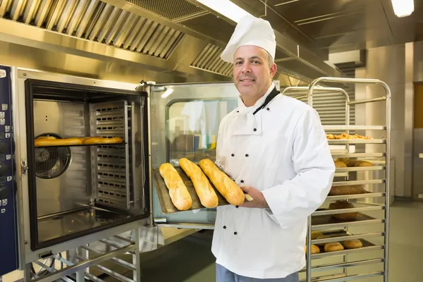 Mature baker showing three baguettes — Stock Photo, Image