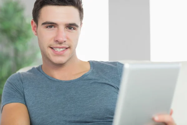 Happy handsome man relaxing on couch using tablet — Stock Photo, Image