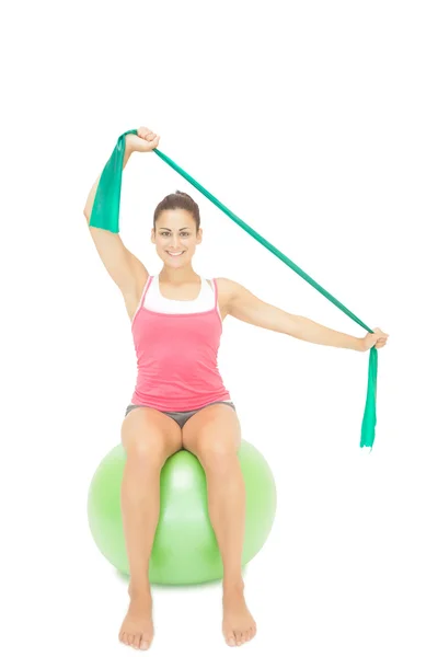 Gleeful sporty brunette stretching with resistance band — Stock Photo, Image