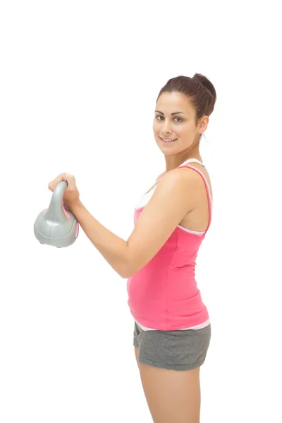 Pretty sporty brunette holding grey and pink kettlebell — Stock Photo, Image