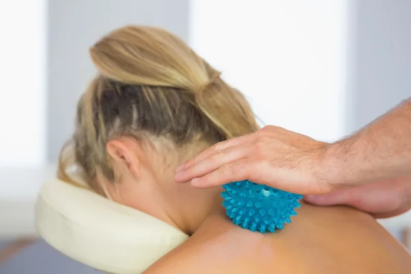 Fisioterapeuta massageando paciente feminino com bola de massagem azul — Fotografia de Stock